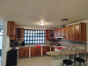 a kitchen with wooden cabinets and a island with chairs at Casa Lago de Luz in San Juan Cosalá