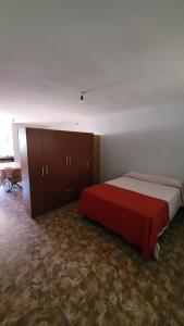 a bedroom with a large bed with a red blanket at Monoambiente La Falda in La Falda