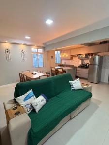 a living room with a green couch and a kitchen at 1101 Barra Salvador - Excelente para o Carnaval! in Salvador