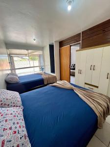two beds in a bedroom with blue sheets at 11-Casa espaçosa com garagem e Wi-Fi in São Leopoldo