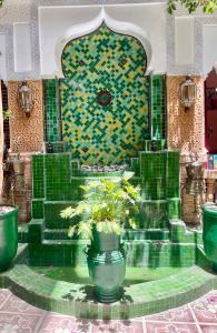 a fountain in a building with a green and yellow wall at Riad Olivier Marrakech medina in Marrakesh