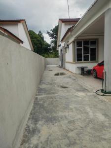 a driveway in front of a house with a red car at Homestay Sulong in Kuala Rompin