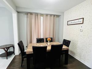a dining room with a wooden table and black chairs at The Grand Maple Residence in Brampton