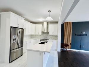 a kitchen with white cabinets and a stainless steel refrigerator at The Grand Maple Residence in Brampton