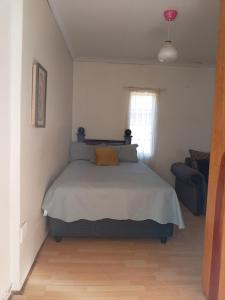 a bedroom with a bed and a chair and a window at Benema's Rest in Waterval Boven
