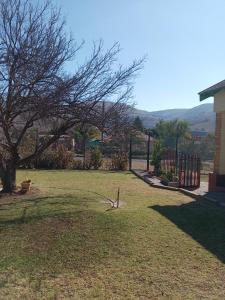 a yard with a fence and a tree in the grass at Benema's Rest in Waterval Boven