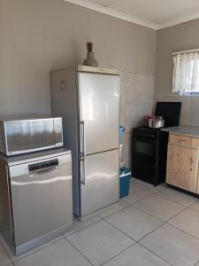 a kitchen with a white refrigerator and a microwave at Benema's Rest in Waterval Boven +2 photos