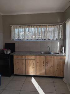 a kitchen with wooden cabinets and a sink and a window at Benema's Rest in Waterval Boven