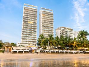 two tall buildings on a beach with palm trees at Resort Playa Azul Departamentos Frente al Mar in Tonsupa