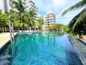 a swimming pool with blue water and palm trees at By The Sea - UBTS SMART ENTERPRISE in Batu Ferringhi