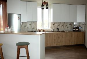 a kitchen with white cabinets and a bar with a stool at NIISS house in Akhaltsikhe +27 photos