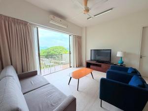 a living room with a couch and a tv at By The Sea - UBTS SMART ENTERPRISE in Batu Ferringhi