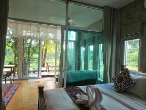 a bedroom with a bed and a large glass window at Nan De Panna Homestay in Nan