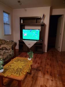 a living room with a tv and a table at Casa Labranza estacionamiento 2 dormitorios amoblada Jorge Alessandri 0979 in Temuco