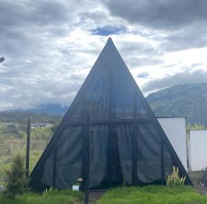 a pyramid shaped building with glass windows in a field at Tungurahua Eco Lodge INN BAÑOS in Quillullaco