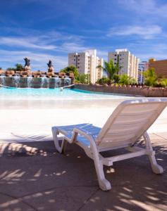 a white chair sitting in front of a swimming pool at ARARAS Apart Hotel - CTC in Caldas Novas