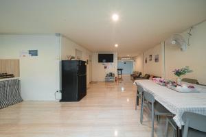 a living room with two tables and a black refrigerator at GAO Phala Beachfront Hostel in Ban Phala