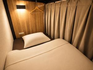 a small room with a bed and a pillow at Namba Guesthouse HIVE in Osaka