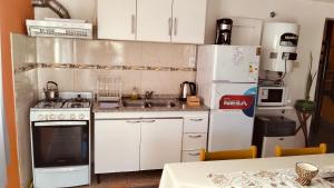 a kitchen with white cabinets and a white refrigerator at Mí cielo in Huerta Grande +12 photos