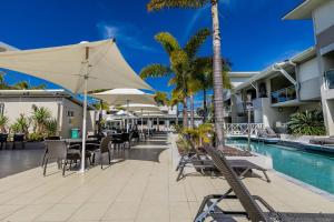 a resort patio with tables and chairs and a pool at Lagoons Resort Studio 64 in Agnes Water