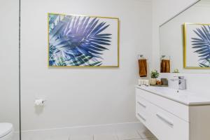 a white bathroom with a sink and a toilet at Lagoons Resort Apartment 63 in Agnes Water +18 photos