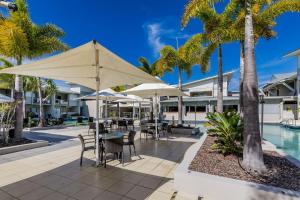 a patio with tables and umbrellas next to a pool at Lagoons Resort Apartment 63 in Agnes Water