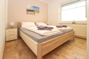 a bedroom with a bed with white sheets and a window at Deichbrise in Greetsiel