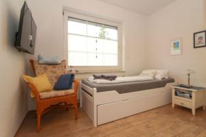 a bedroom with a bed and a chair and a window at Deichbrise in Greetsiel