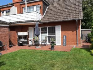 a house with a patio with a table and an umbrella at Deichbrise in Greetsiel
