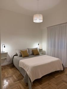a white bedroom with a bed and a pendant light at Colón 2 in Mar del Plata