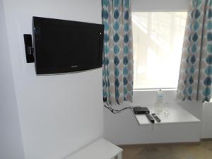 Elle comprend une télévision à écran plat suspendue sur un mur à côté d'une fenêtre. dans l'établissement Bed aan zee Kabine7, à Coxyde