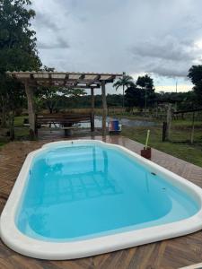 a large blue pool on a deck with a pergola at Refúgio Mix Pousada com 3 suítes e 9 camas in Vilhena