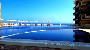 a large swimming pool with umbrellas on a building at قرية بلوباى مرسي مطروح in Marsa Matruh +14 photos