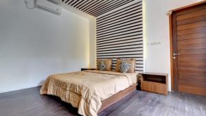 a bedroom with a bed and a wooden door at Villa Maeni in Munggu