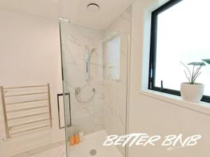 a shower with a glass door in a bathroom at Quiet Haven Retreat | Cozy Modern Townhouse in Lower Hutt +25 photos