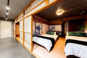 two beds in a room with wooden walls at OZ nikko in Nikko