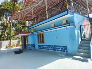 a blue building with a staircase and a balcony at Tranquil Breeze Stay in Napoklu +8 photos