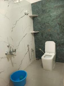 a bathroom with a toilet and a blue bucket at Tranquil Breeze Stay in Napoklu