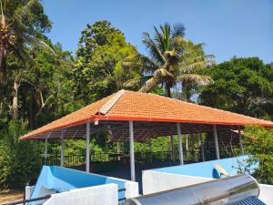 an orange roof on a building with trees in the background at Tranquil Breeze Stay in Napoklu