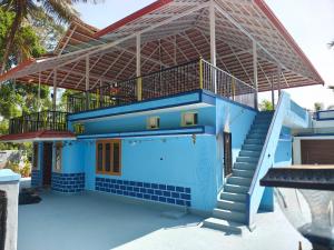 a blue house with a staircase in front of it at Tranquil Breeze Stay in Napoklu