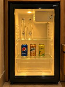 an open refrigerator with drinks and cans in it at Toot Suites Studio in Abha