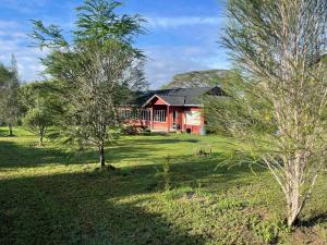 a red house in the middle of a field with trees at Eschato tented camp in Gilgil