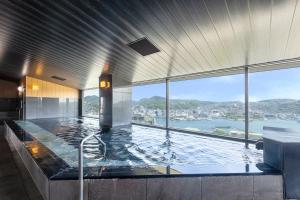 a large swimming pool in a building with a view at Ooedo Onsen Monogatari Premium Nagasaki Hotel Seifu in Nagasaki