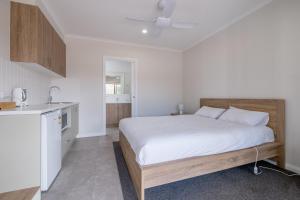 a white bedroom with a bed and a kitchen at Beaufort Lake Caravan Park in Beaufort