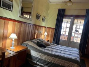 a bedroom with a bed with two lamps and a mirror at Amura Hostel in Puerto Varas