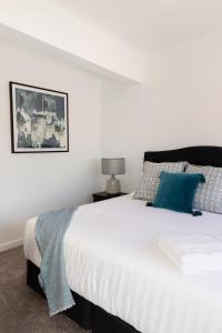 a bedroom with a large white bed with blue pillows at The Lime Loft, Rooftop Views in Mildura's CBD in Mildura