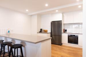 a kitchen with a stainless steel refrigerator and stools at The Lime Loft, Rooftop Views in Mildura's CBD in Mildura
