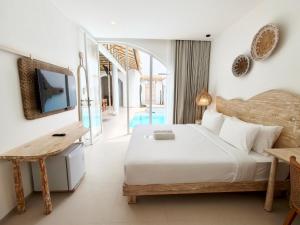 a bedroom with a bed and a desk and a tv at Villa Nala Uluwatu by LODGELINK BALI in Uluwatu