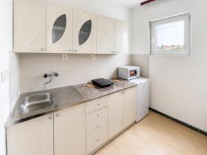 a kitchen with white cabinets and a sink and a window at Apartment Pasic in Petrovaradin