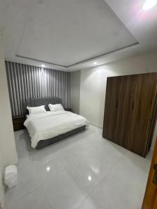 a bedroom with a white bed and a wooden cabinet at شقة غرفة وصالة in Musaylah